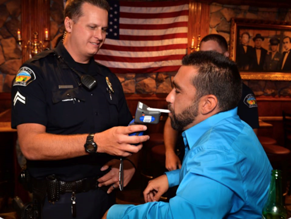 Person blowing into an alcohol volume testing device, or breathalyzer.