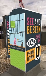 Traffic signal cabinet with the message See and Be Seen. Eyes Up, Phones Down.