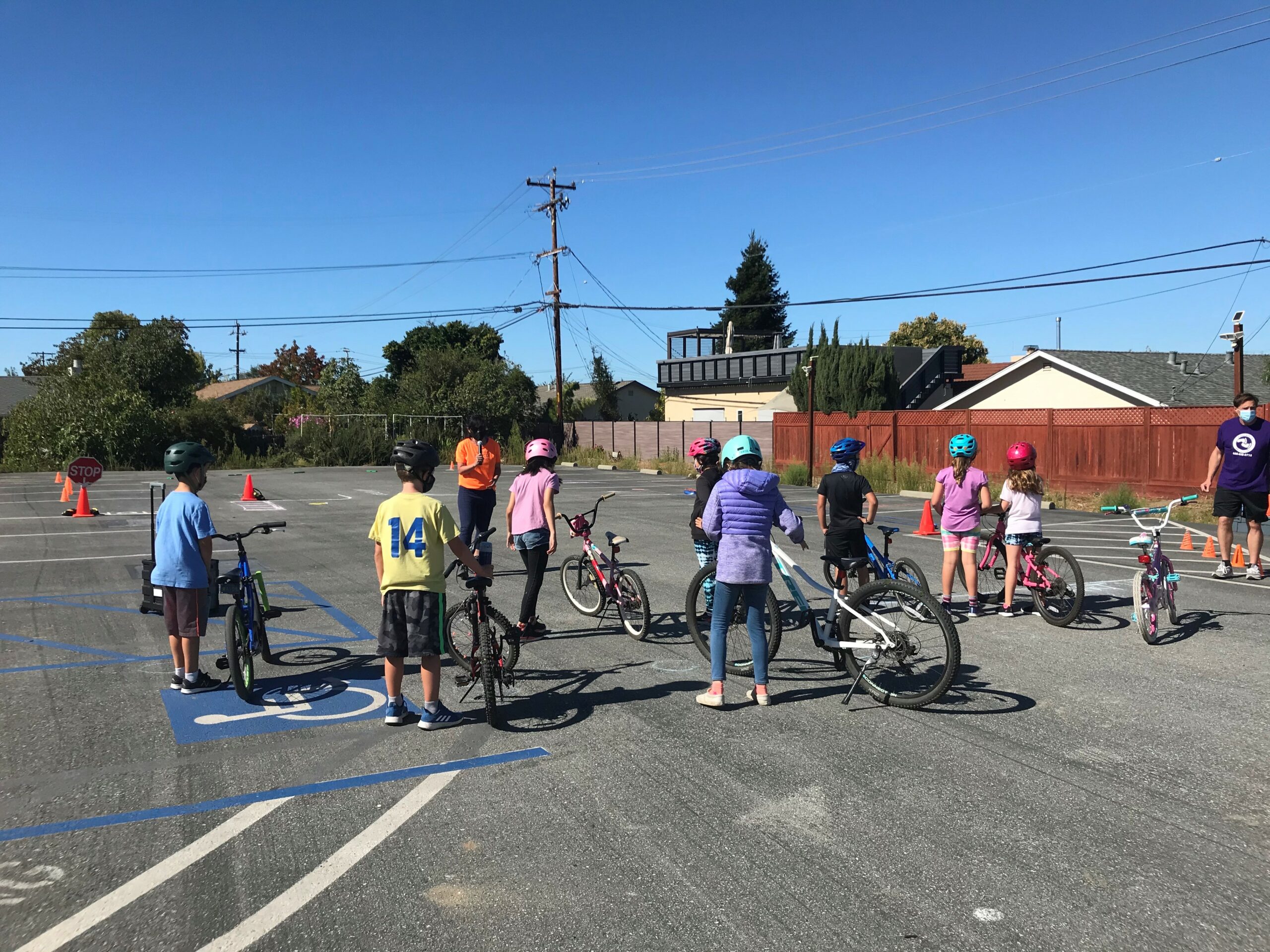 Image of kids standing in parking lot on bikes with helmets