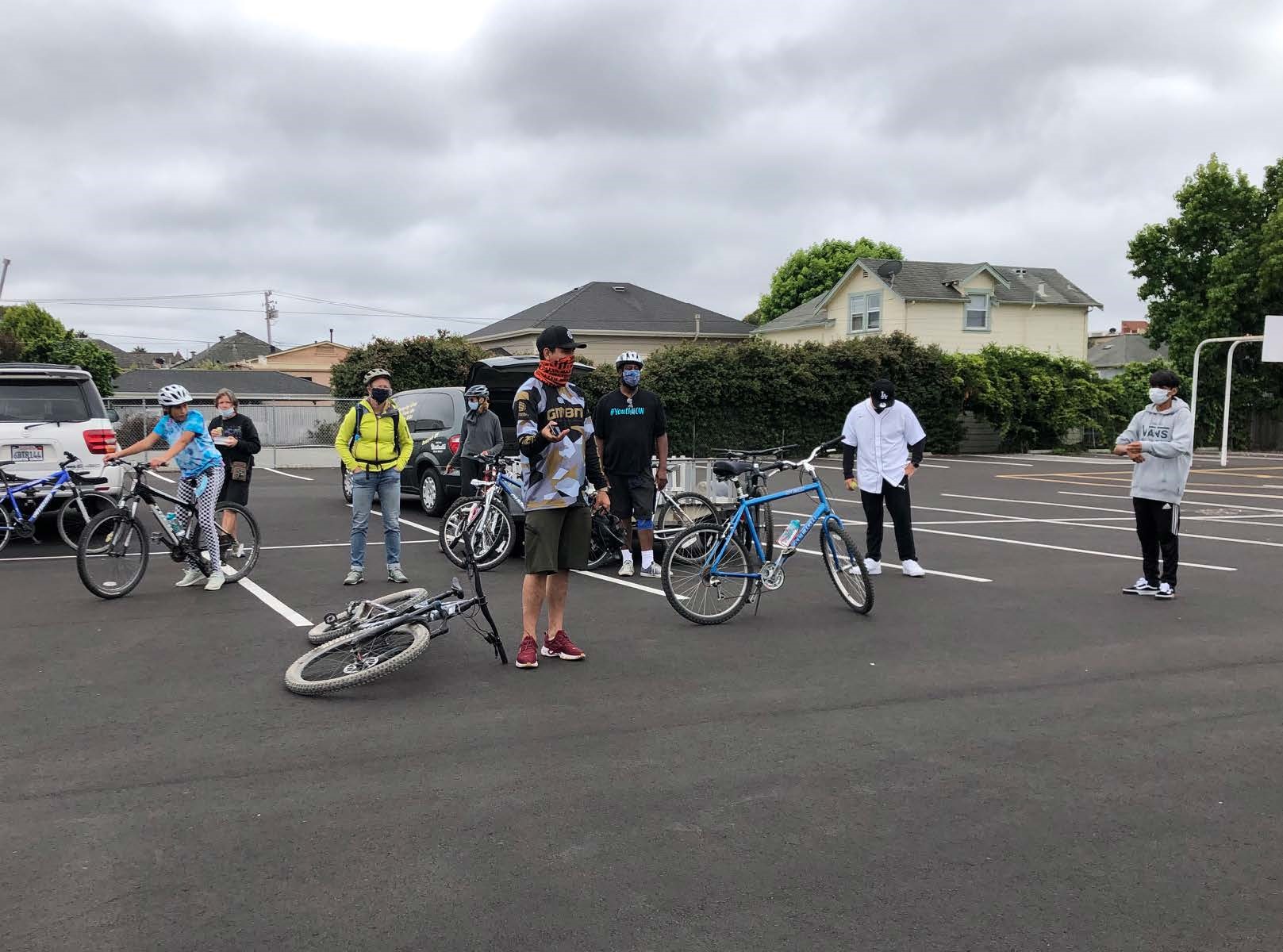 A group of people standing in a parking lot with bicycles during training