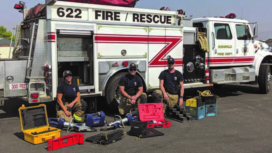 Image of firefighters with extrication equipment displayed in front of a fire truck
